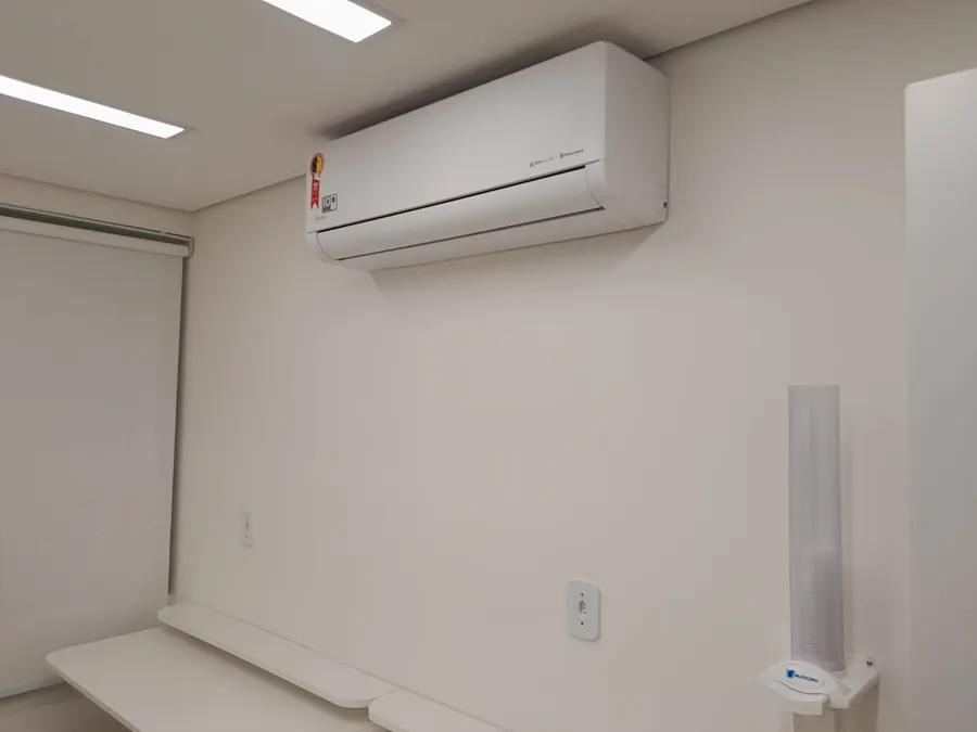 Evaporadora de ar-condicionado tipo split instalada em parede de ambiente corporativo já acabado.